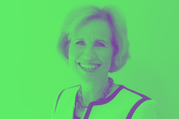 A woman is smiling in front of a green background.