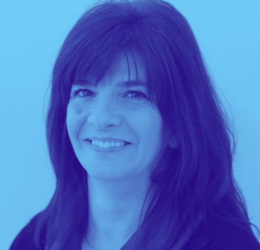 A woman with long hair is smiling in a blue background.