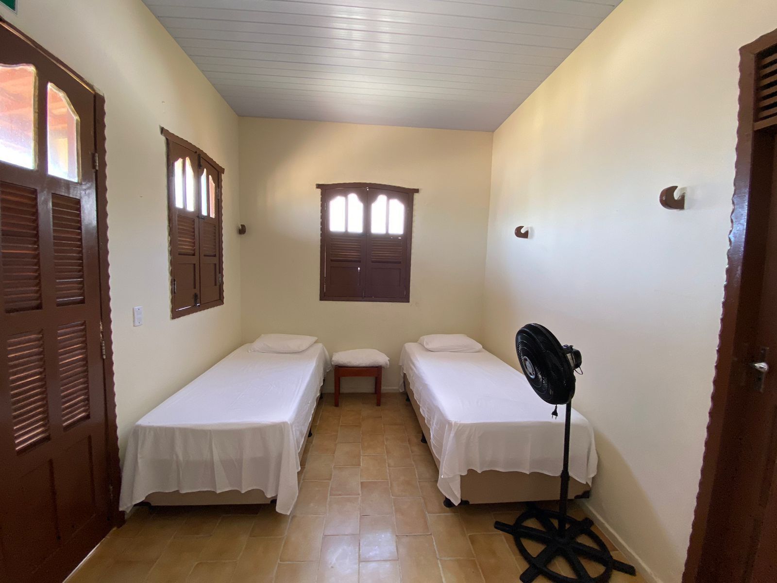 Um quarto com duas camas e um ventilador