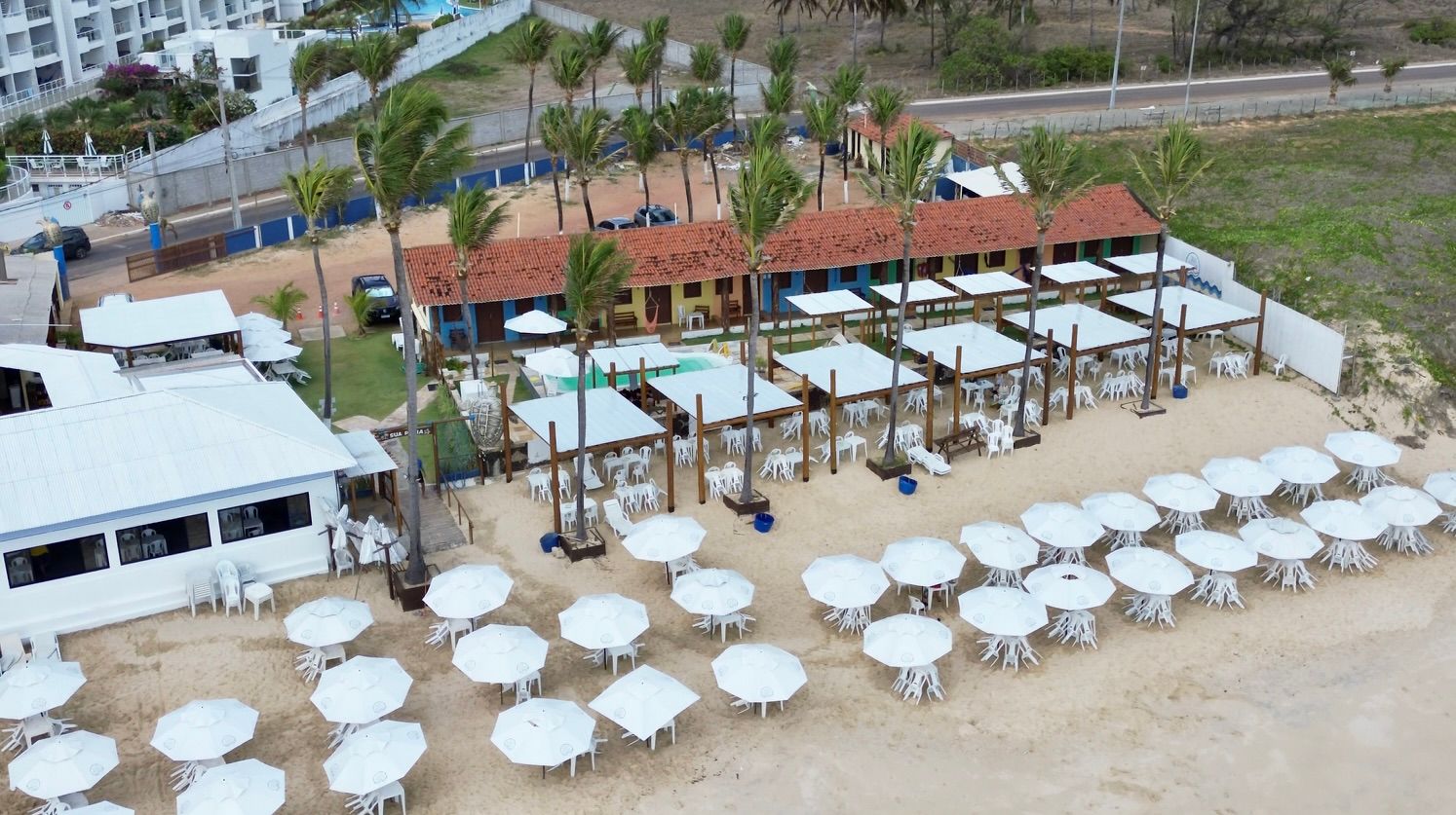 Uma vista aérea de uma praia com mesas e guarda-sóis