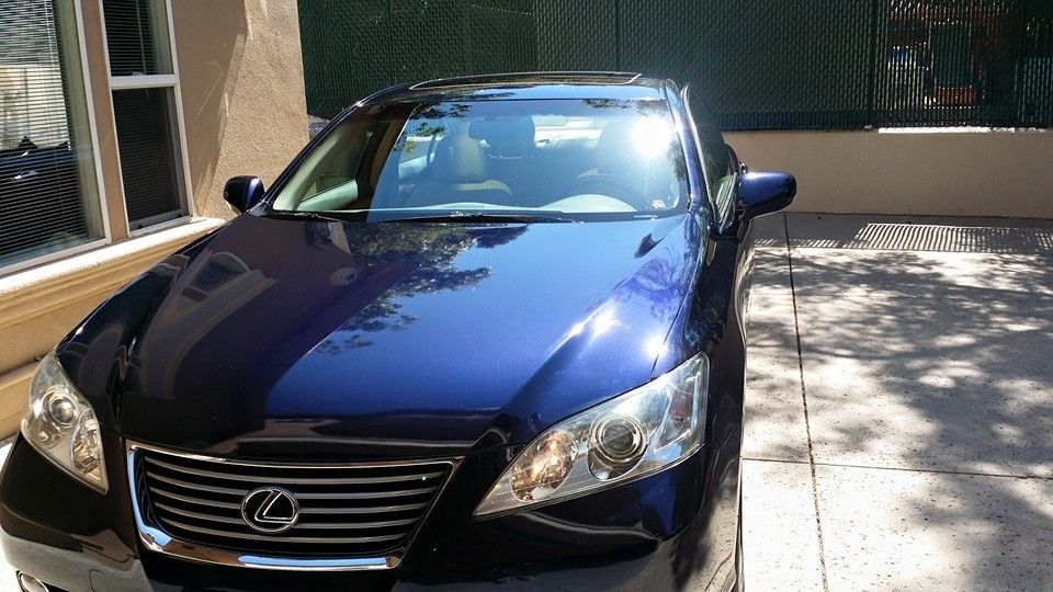 A blue lexus is parked in front of a building