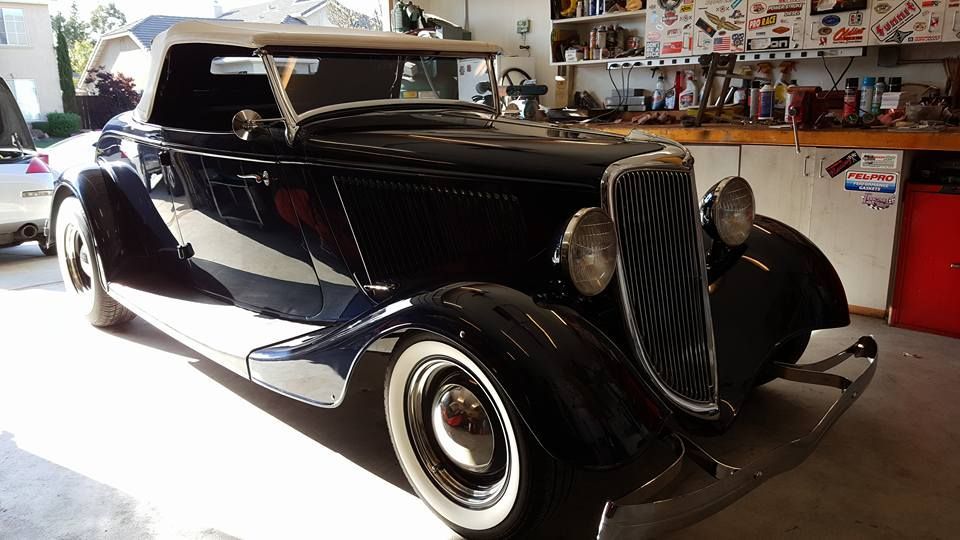A red tesla model x with its doors open is parked in a driveway.