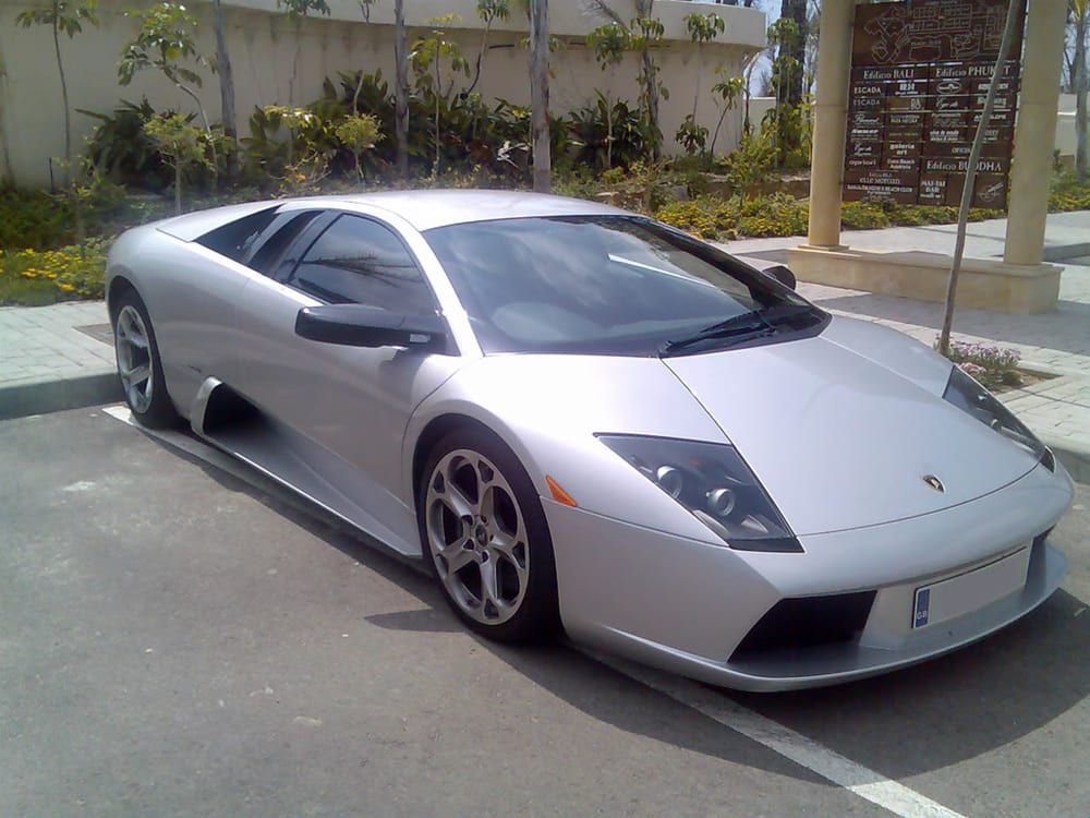 A silver lamborghini is parked in a parking lot