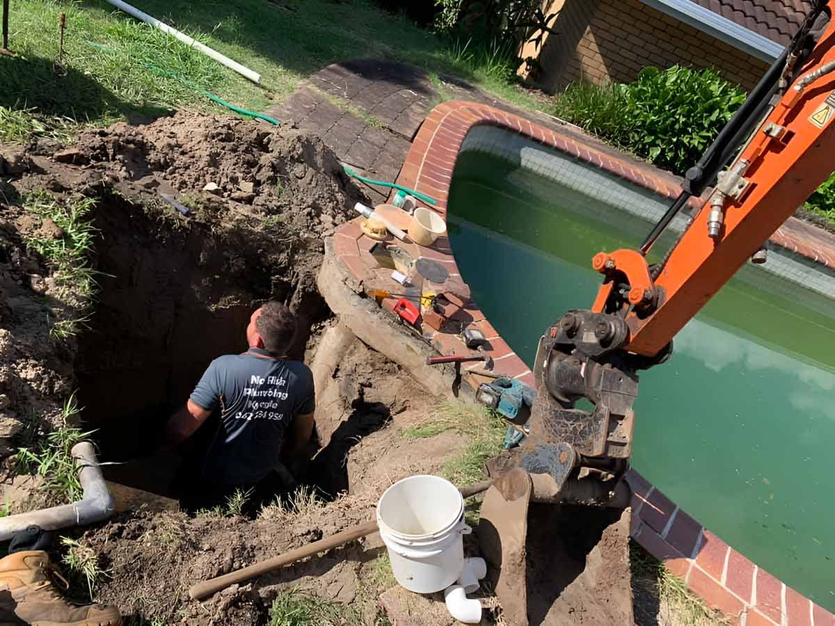 A Man Is Digging A Hole In The Ground Next To A Pool — No Risk Plumbing Kyogle Pty Ltd in Geneva, NSW