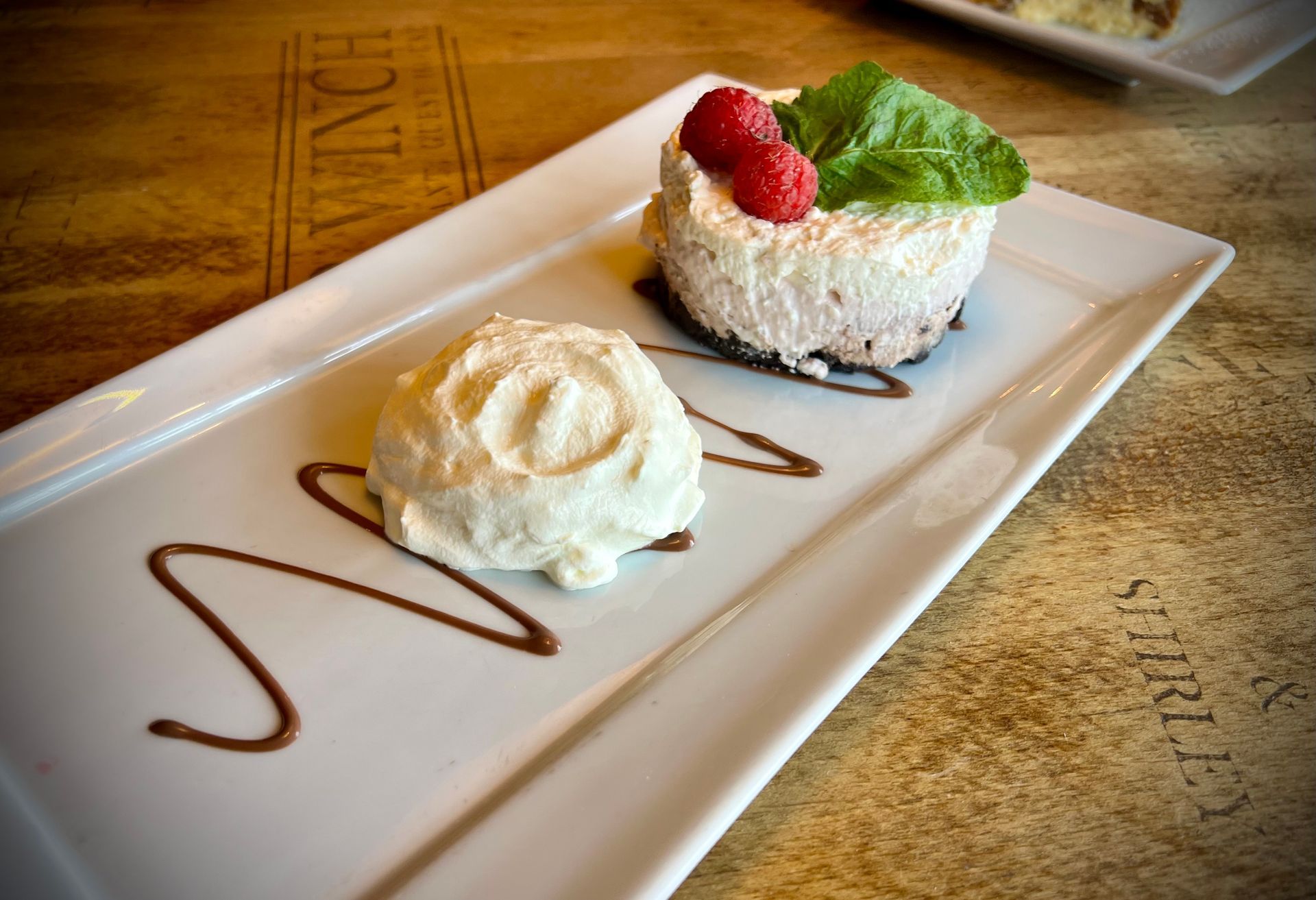 Creamy cheesecake with a chocolate base, fresh raspberries and whipped cream.