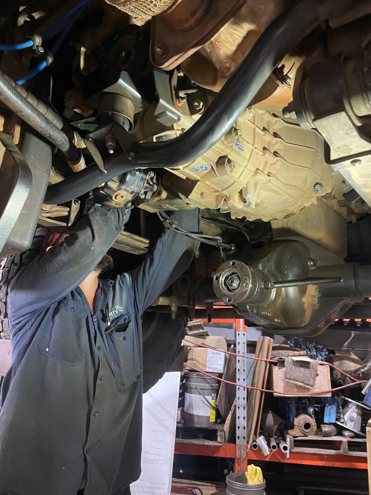 A Man Is Working Underneath A Car In A Garage — McLaren Engineering in Atherton, QLD