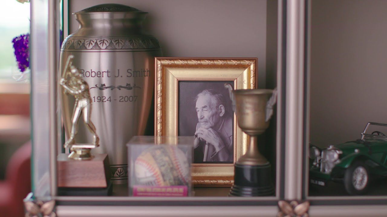 A personalized memoriam for an old man including a baseball trophy and a baseball.
