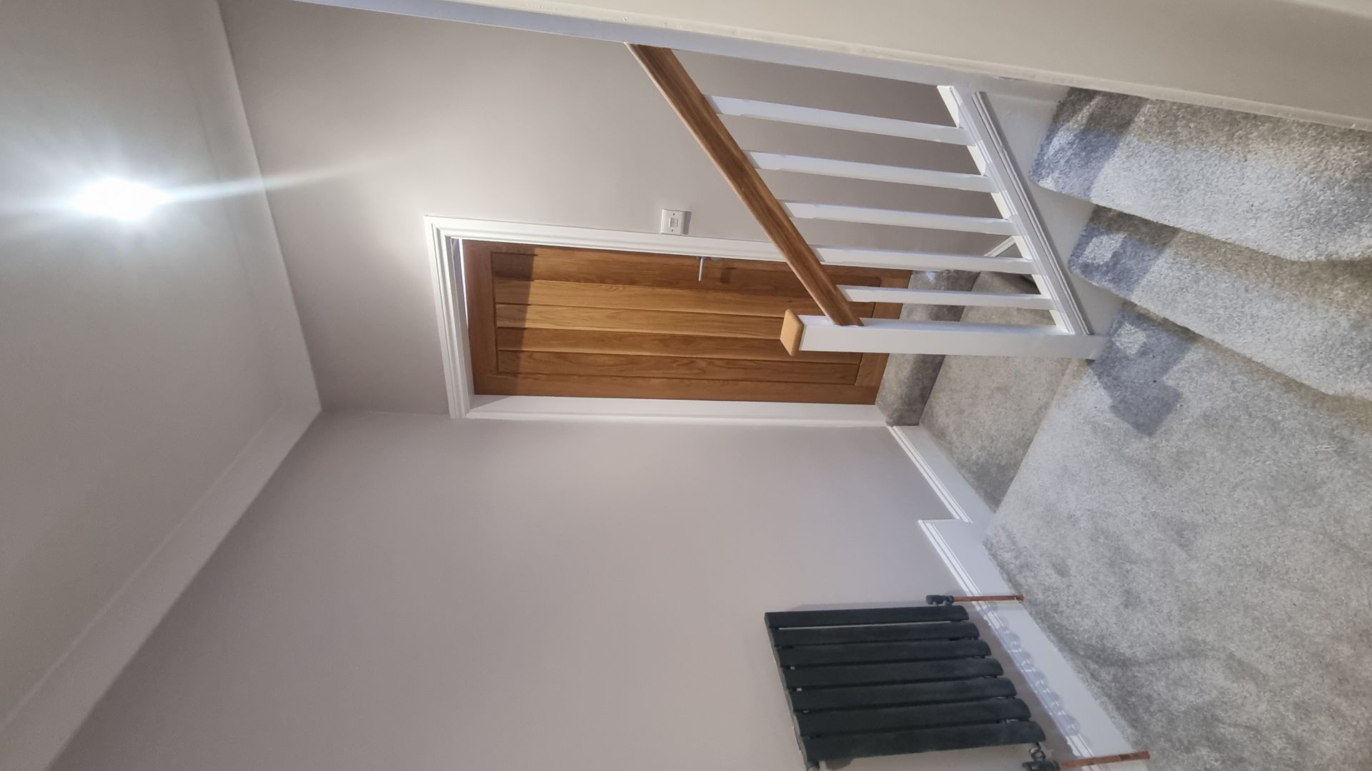 Modern staircase renovation featuring wooden railings and light grey carpet in York.