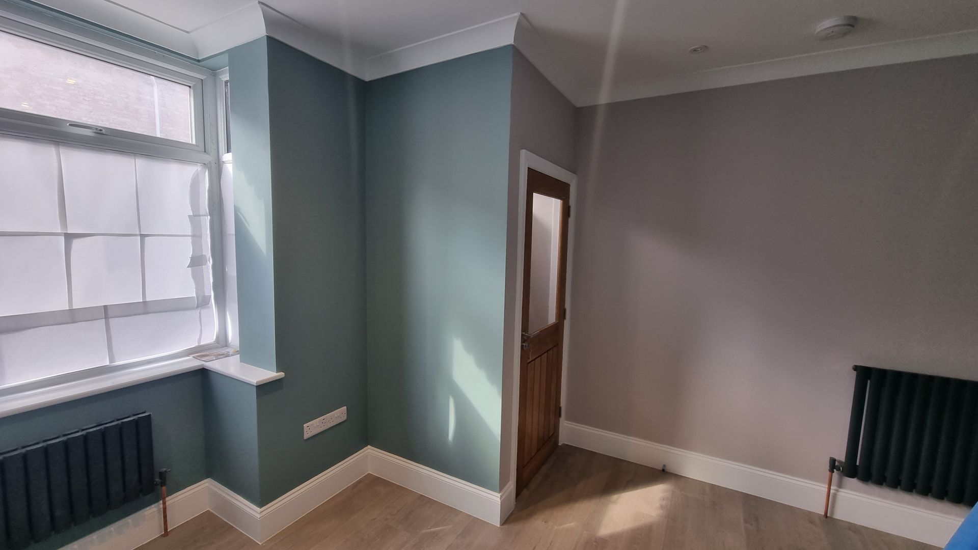 Stylish hallway renovation with light blue walls, wooden door, and natural light in York.