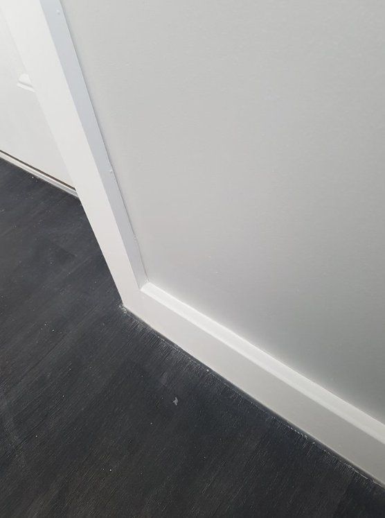 Close-up of newly painted white skirting board and dark grey flooring in York.