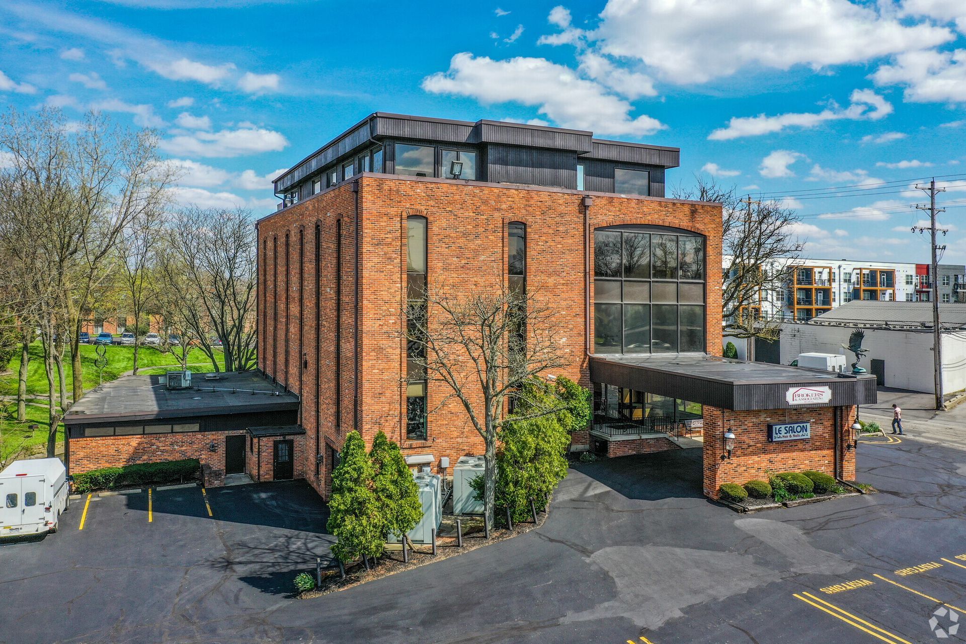 An aerial view of a large brick building with a parking lot in front of it.