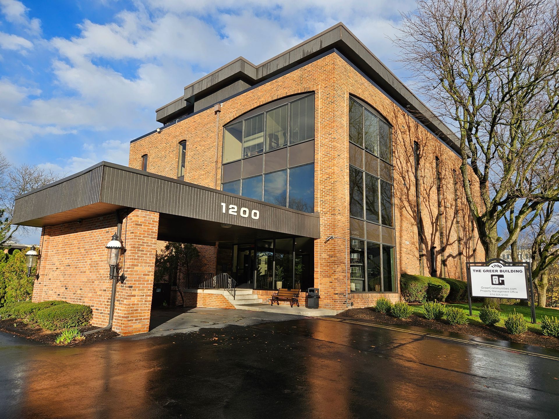 A large brick building with a lot of windows and a parking lot in front of it.