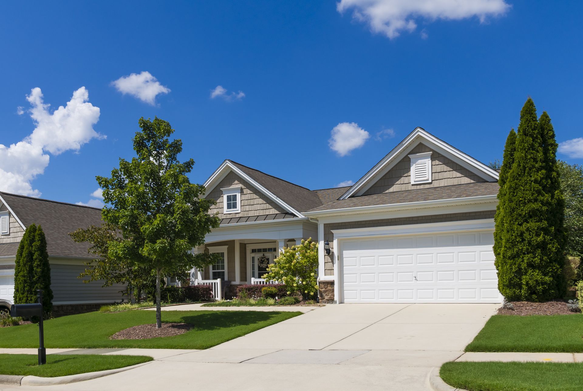 Suburban house with a driveway, garage, and front yard on a sunny day.