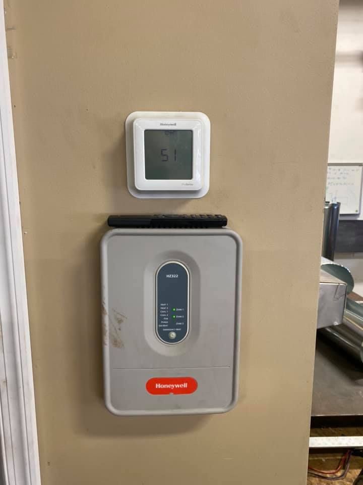 A thermostat and a digital thermometer are mounted on a wall.