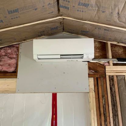 A wall mounted air conditioner is hanging from the ceiling of a room.