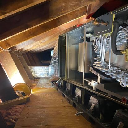A large machine is sitting in the attic of a house.