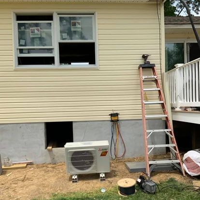 A ladder is sitting on the side of a house next to a window.