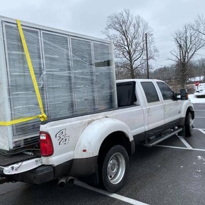 A white truck with a box in the back is parked in a parking lot.