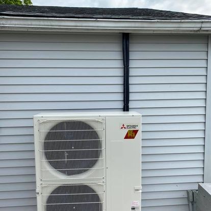 A mitsubishi air conditioner is installed on the side of a house.