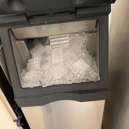 A stainless steel ice maker filled with ice cubes.
