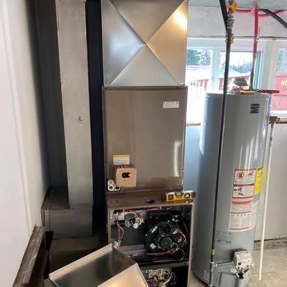 A water heater is sitting next to an air conditioner in a room.