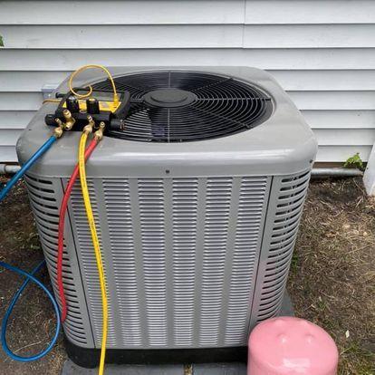 An air conditioner is being serviced outside of a house.