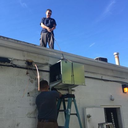 A man standing on a roof next to a man on a ladder
