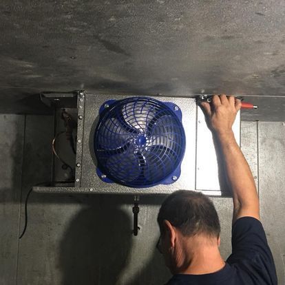 A man is fixing a fan with a screwdriver