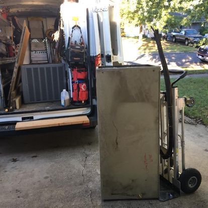 A refrigerator is being moved by a dolly in front of a van