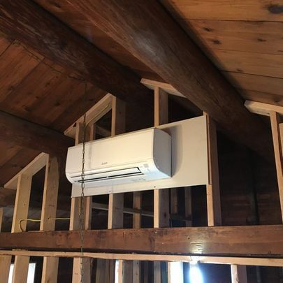 An air conditioner is hanging from the ceiling of a building under construction