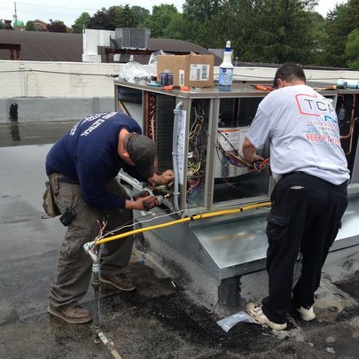 Two men working on a roof with one wearing a tcf shirt