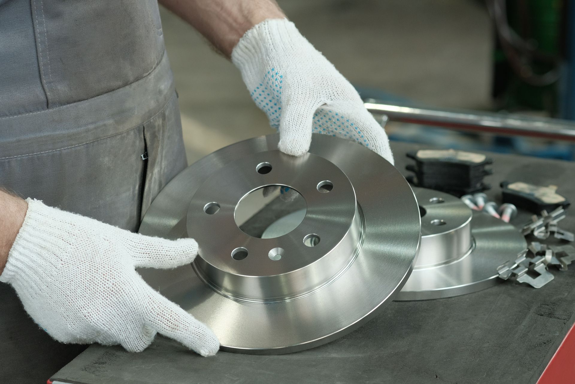 Close-up of a man's hands holding brake parts, showing detailed car components.