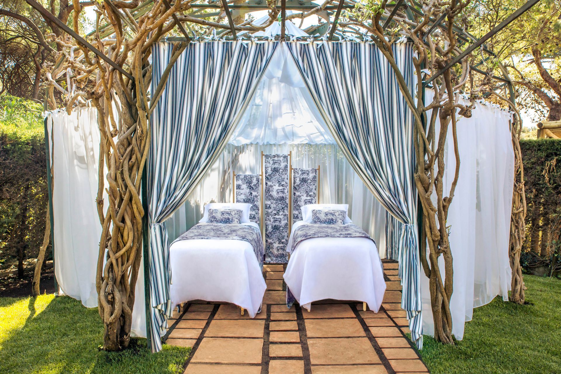 There are two beds under a canopy in the middle of a garden.