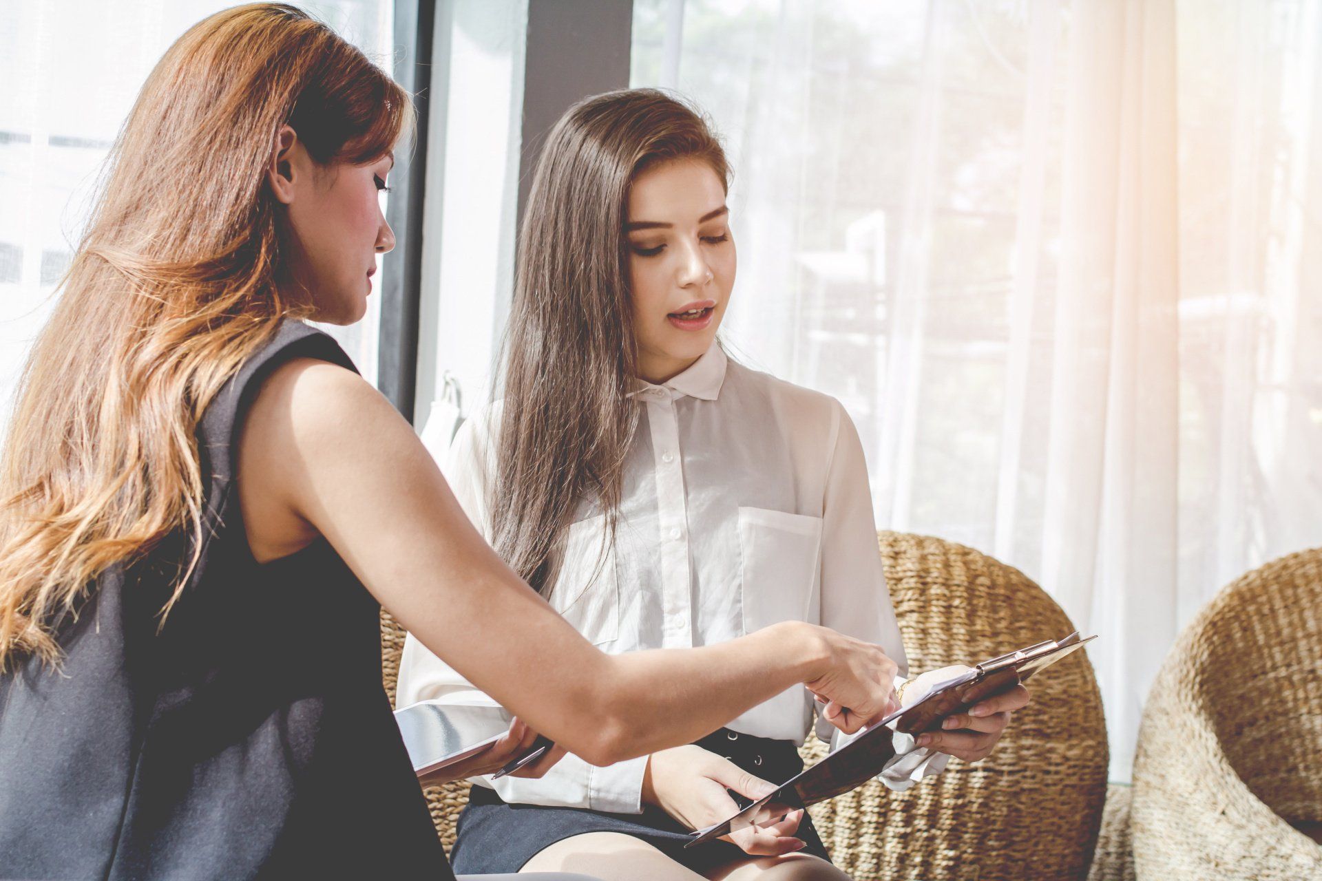 Deux femmes sont assises dans une salle d'attente et regardent un menu.