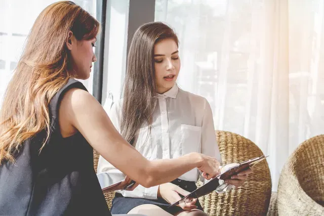 Deux femmes sont assises sur des chaises et regardent un presse-papiers.