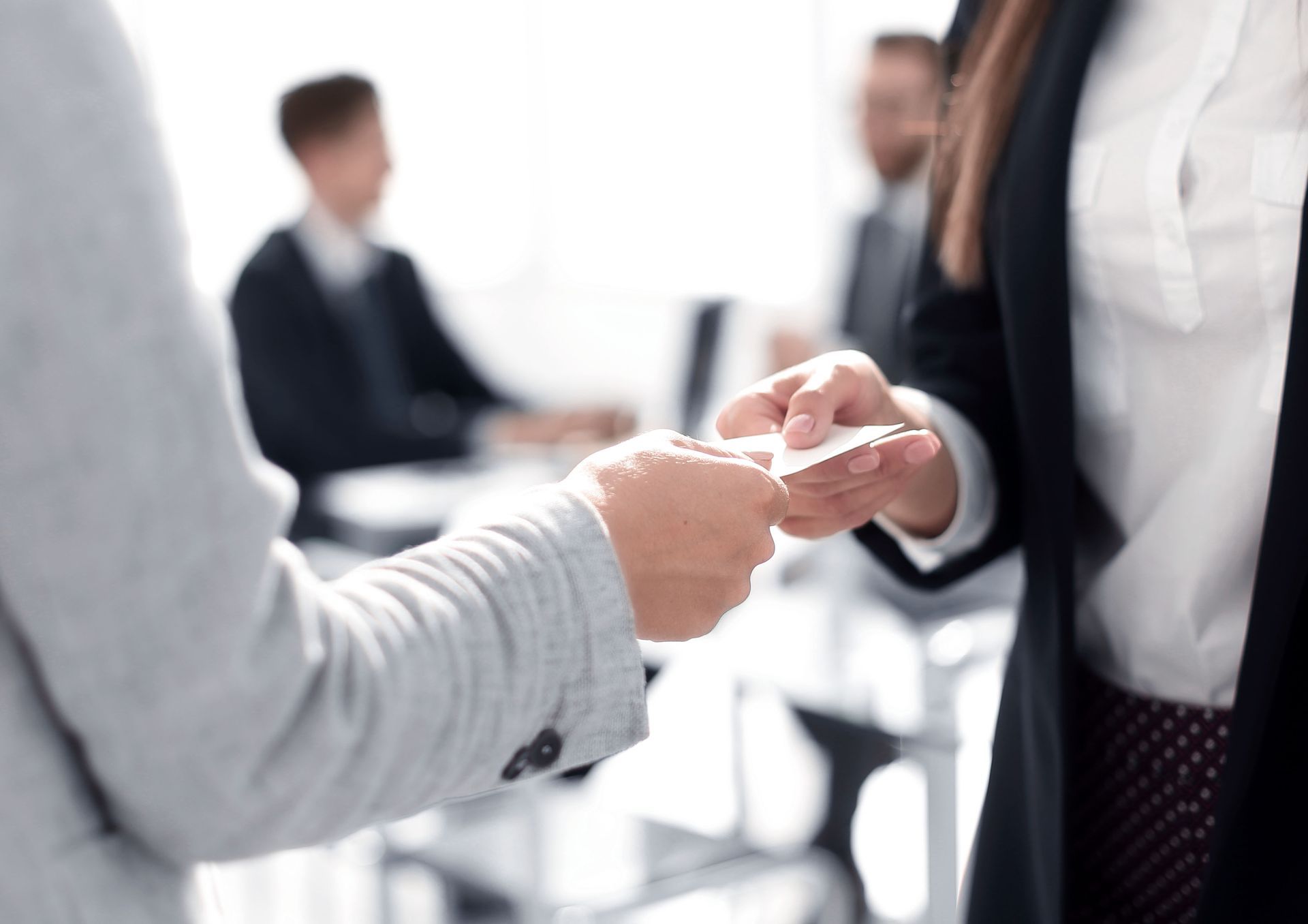 Close-up of two businesswomen exchanging business cards.