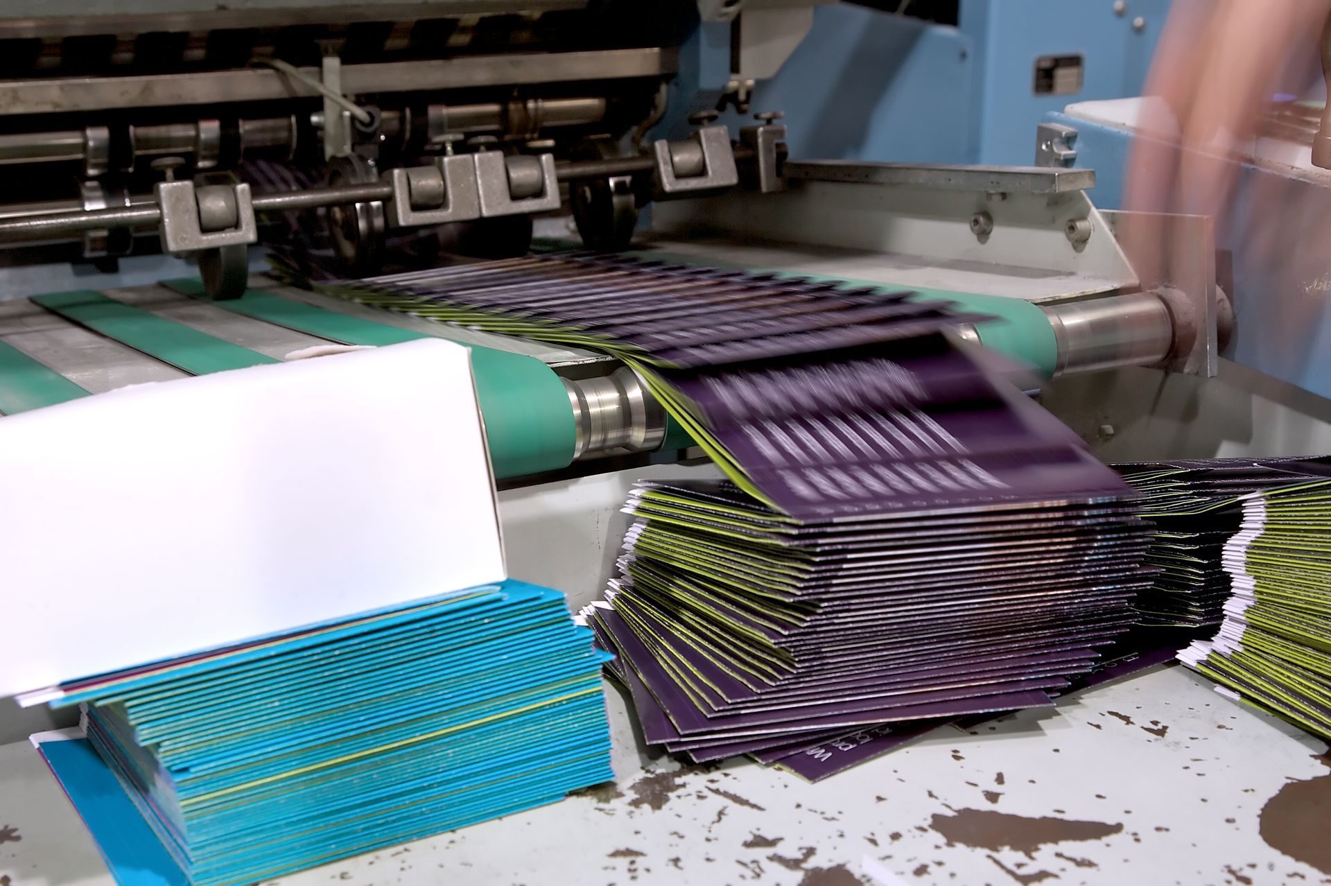 Person in orange shirt handling stack of printed paper in a printing factory.