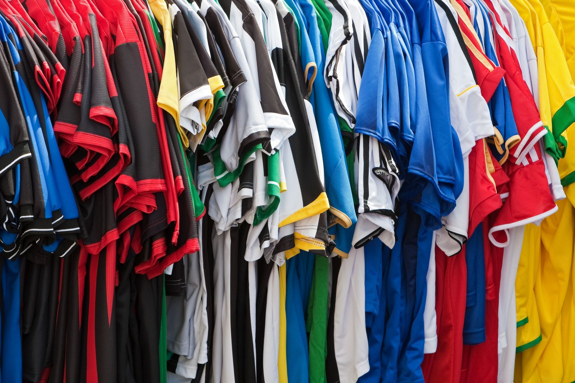 Rows of colorful athletic jerseys hanging on racks.