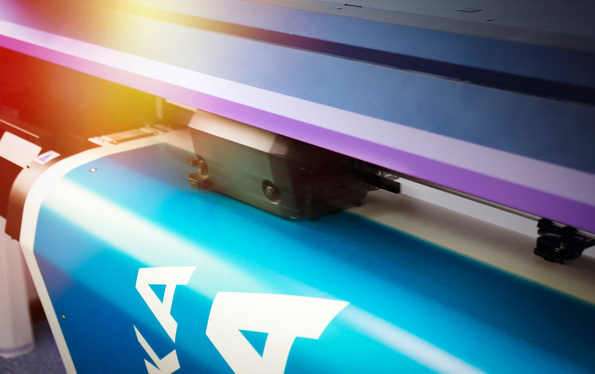 Large-format printer printing a blue sign with a close-up view of the printing head.