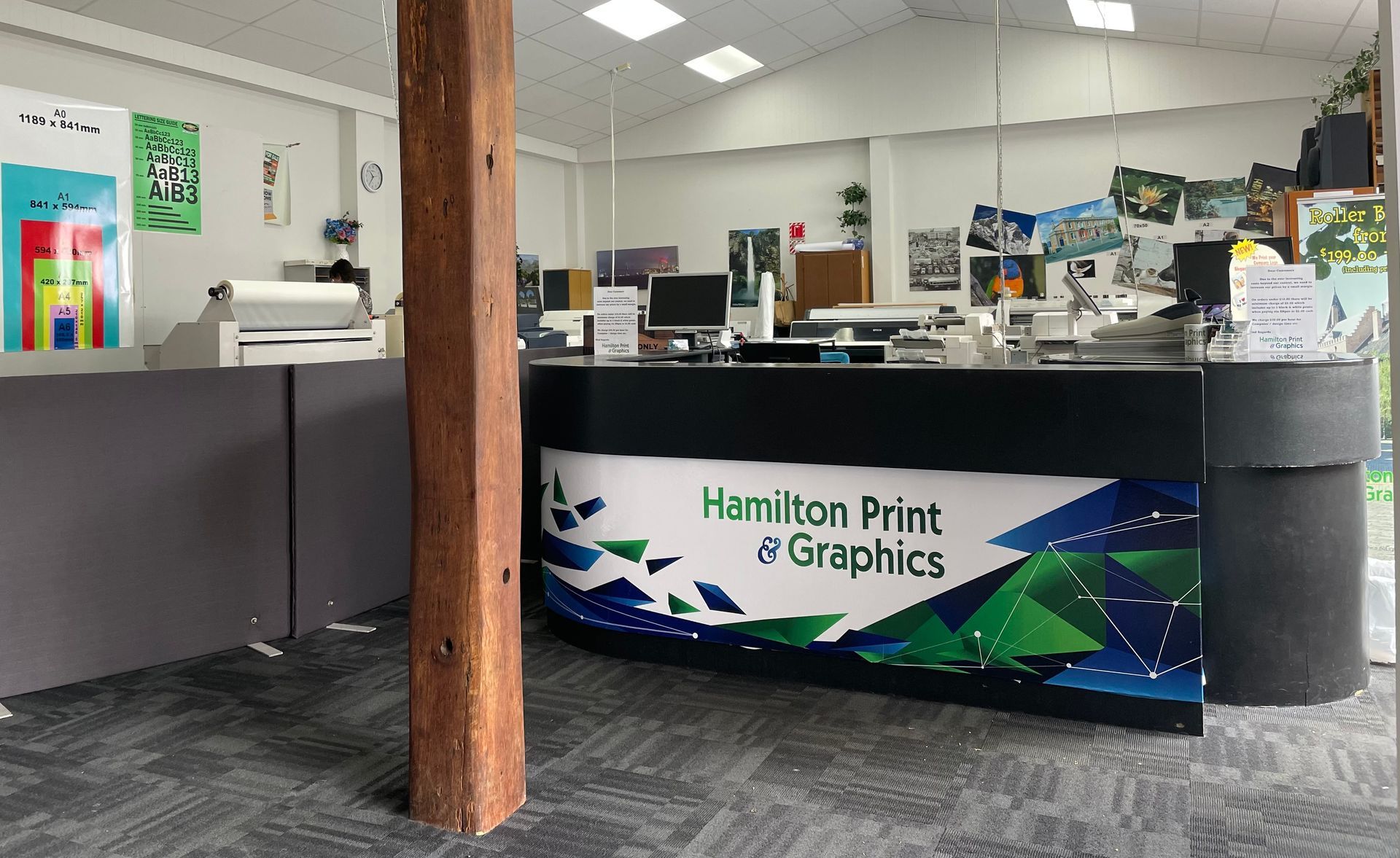 Man in black hoodie operating printing press.