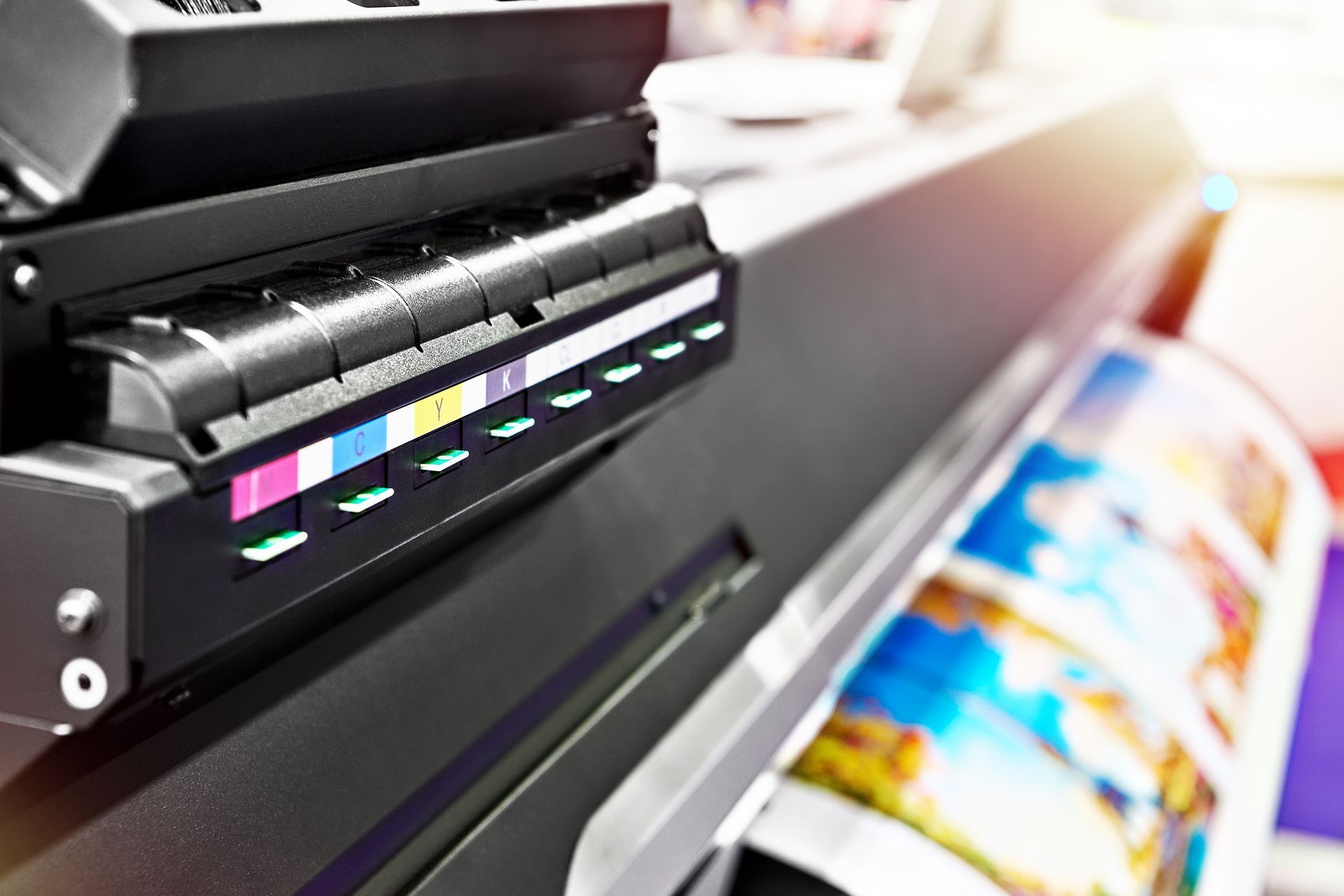 Large format printer printing a colorful image, close-up view. Ink cartridges visible.