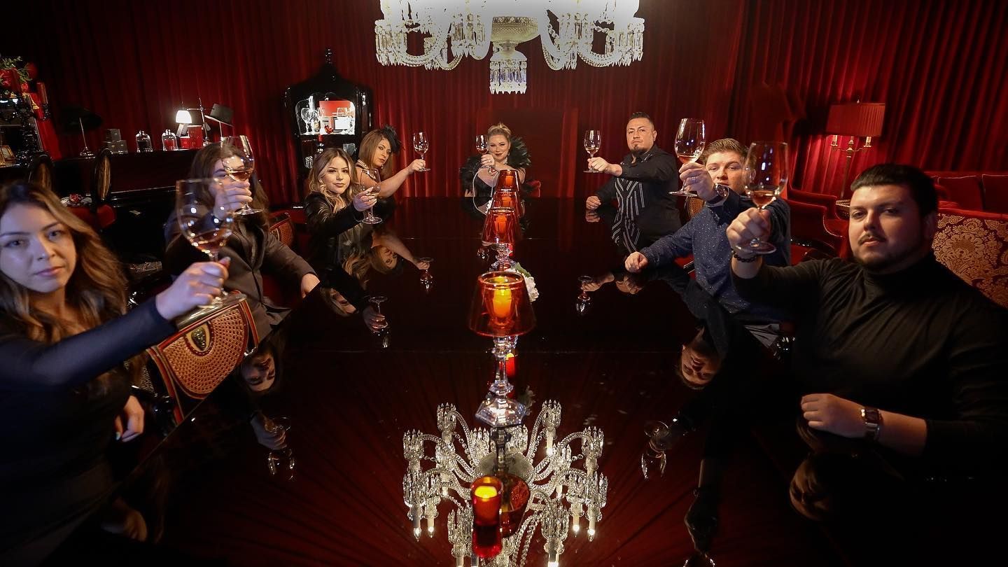 A group of people are standing around a table holding wine glasses.