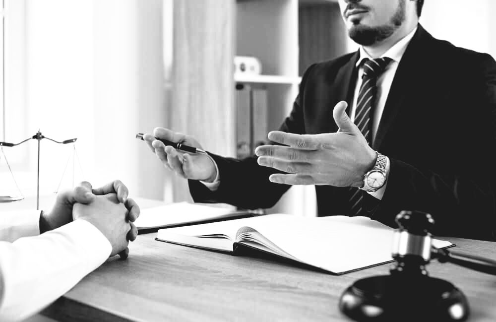 A Lawyer With Blue Suit And Black Pen In Right Hand Explaining To A Client — Farrell Lusher Solicitors In Wagga Wagga, NSW