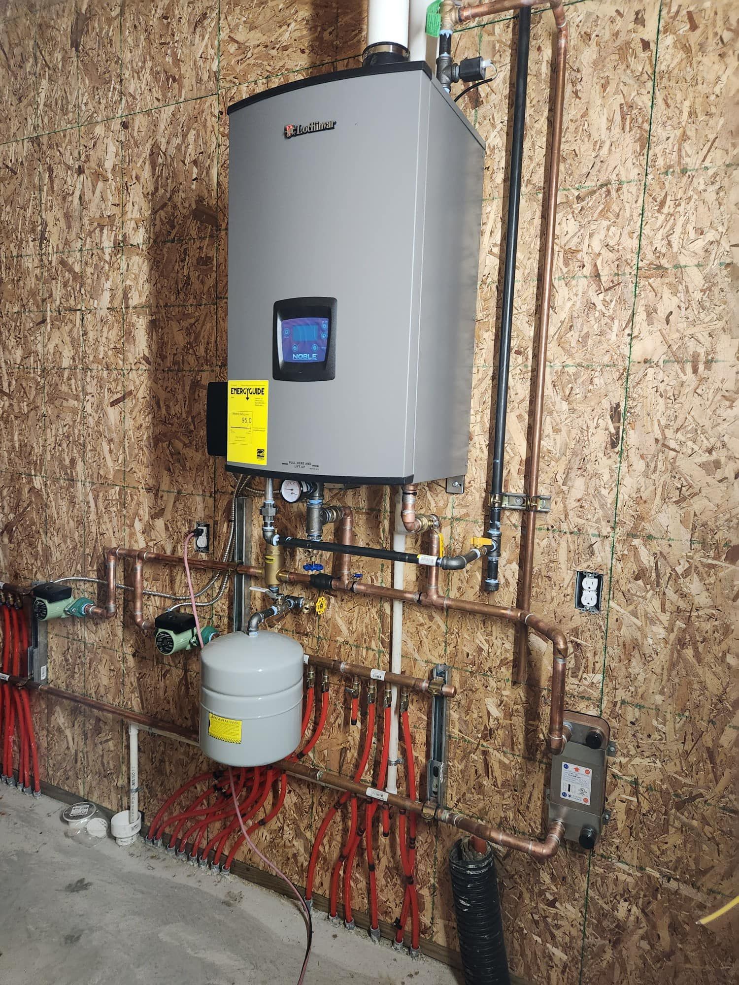 Water heater and related pipes mounted on a wooden wall. Copper pipes and expansion tank are visible.