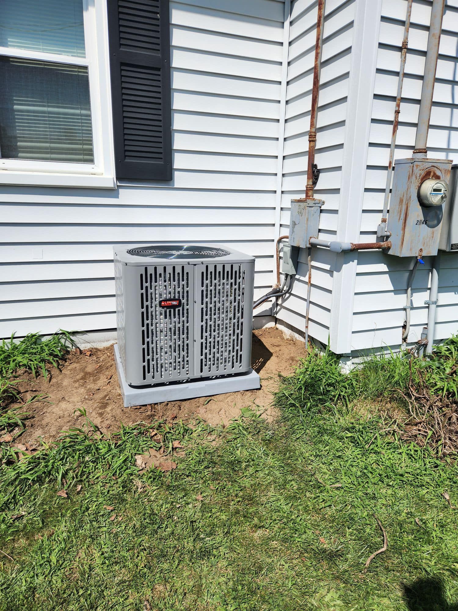 AC unit outside a white house with black shutters, connected to electrical boxes.