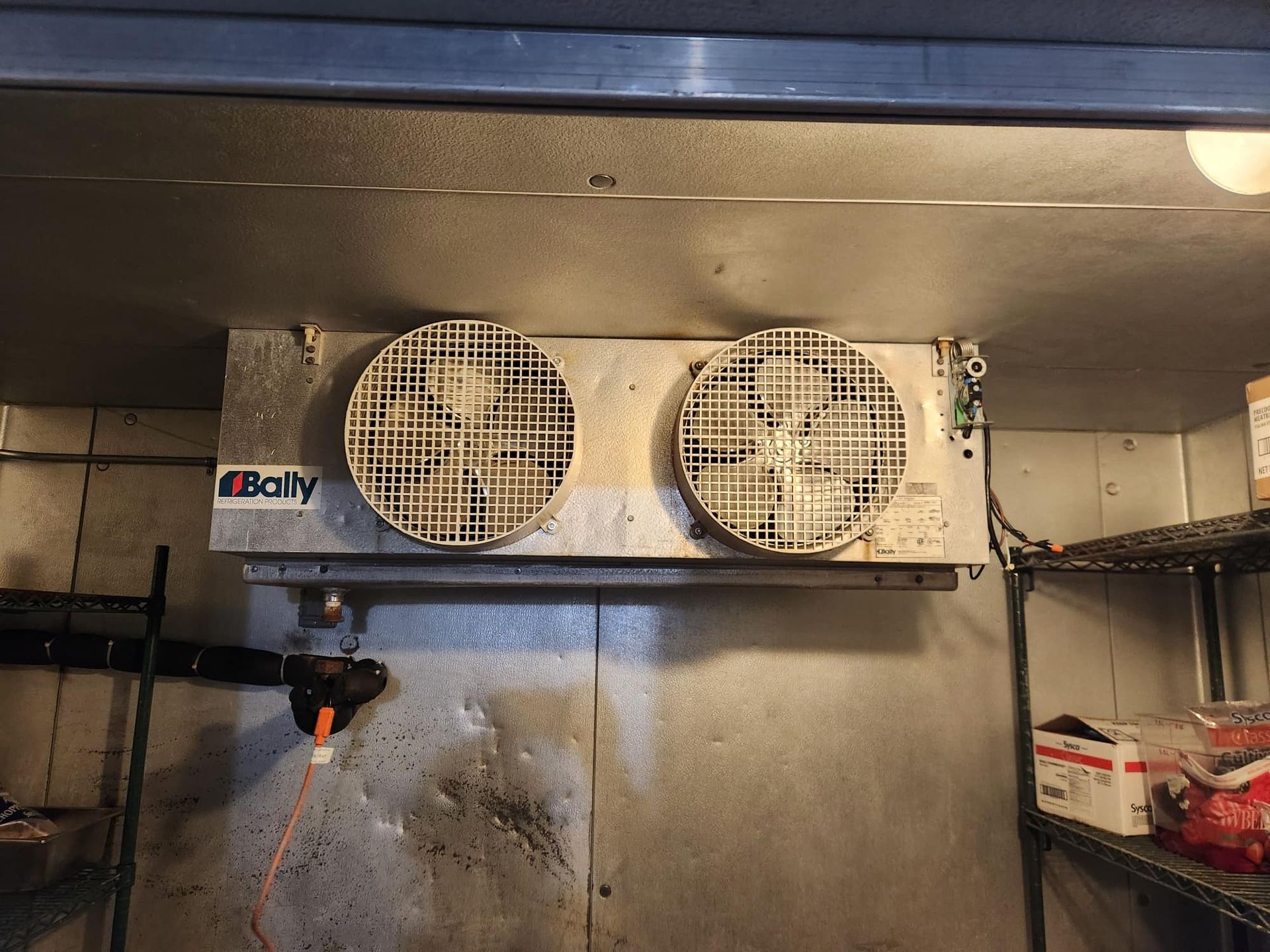 Two fans in a walk-in freezer labeled 