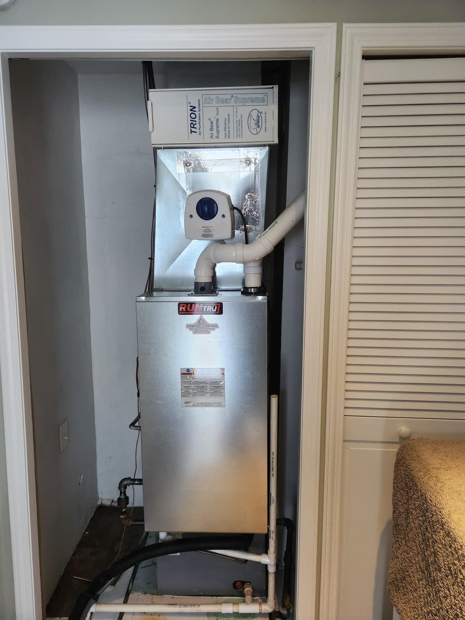 Furnace unit in a closet with ductwork and a PVC pipe.