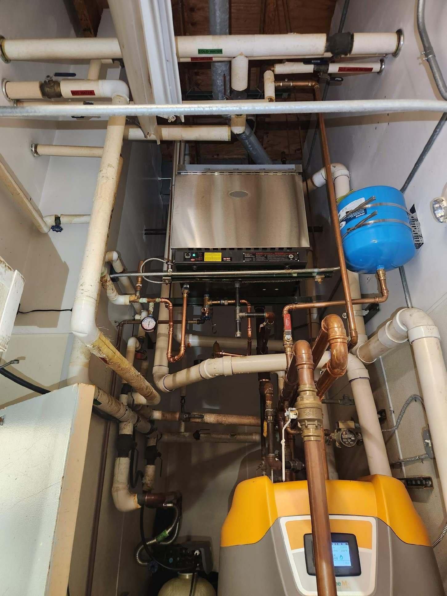 Heating system with pipes, tanks, and a boiler in a utility room.