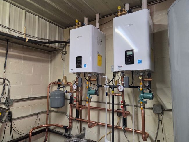 Heating system with stainless steel boiler, yellow tank, blue tank, and various pipes.