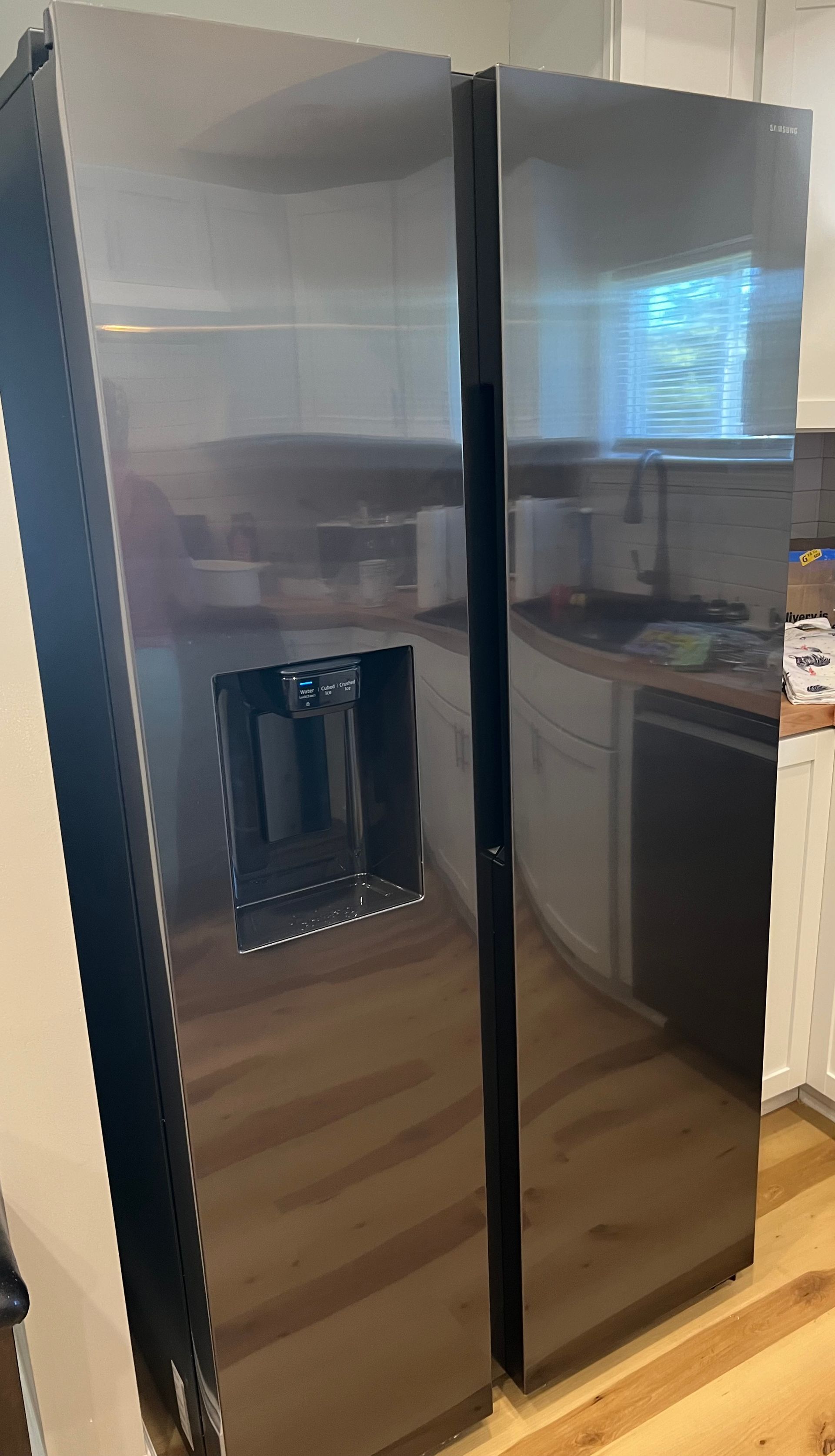 Stainless steel side-by-side refrigerator with water dispenser in a kitchen.